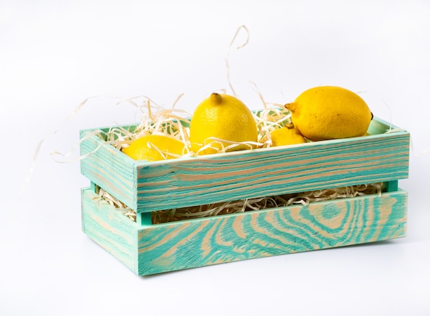 Ripe lemon in wooden box on white