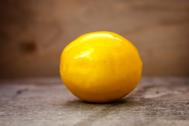 Ripe lemon on a wooden table on a brown background