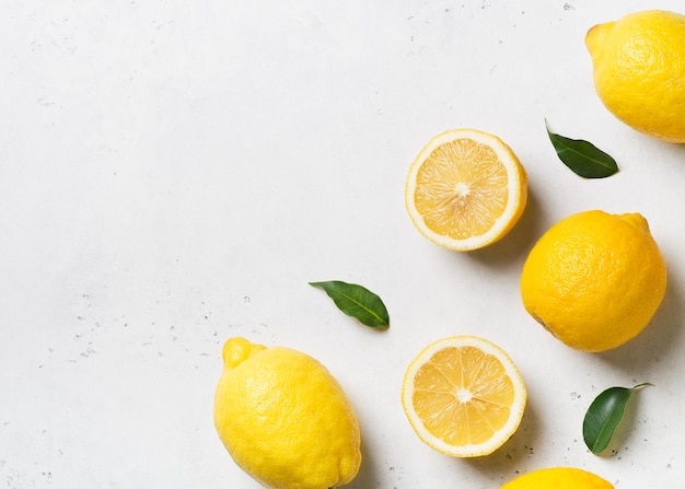 Ripe lemons flat lay with leaves on white. top view