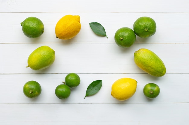 Ripe lemons and limes on white wooden.