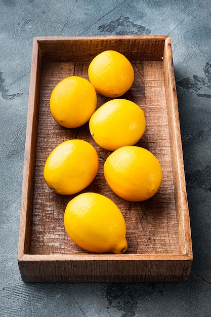 Ripe lemons set, in wooden box, on gray