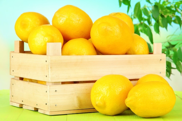 밝은 배경의 탁자 위에 있는 나무 상자에 잘 익은 레몬
