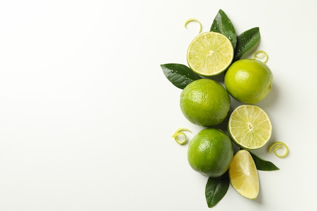 Ripe lime, leaves and peel on white background