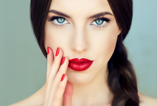 Ripe lips painted in red color long black eyelashes and straight gaze of beautiful eyes Manicure