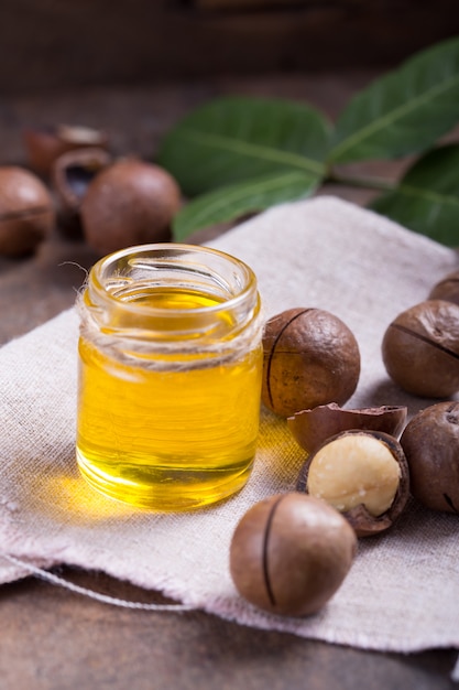 Ripe macadamia nuts and a glass bottle with natural oil