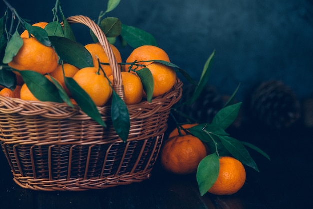 Ripe Mandarin fruit peeled open and place on old rustic look timber with group of mandarin fruits and leaves out of focus on the surface