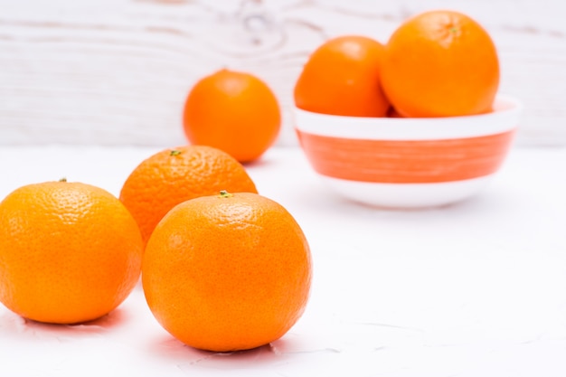 Ripe mandarins on a table and in a bowl