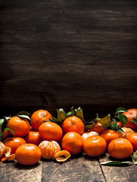 Ripe mandarins with leaves on a wooden background