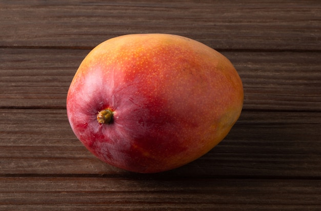 Ripe mango fruit isolated on wooden background.