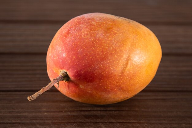 Frutto di mango maturo isolato su sfondo di legno.