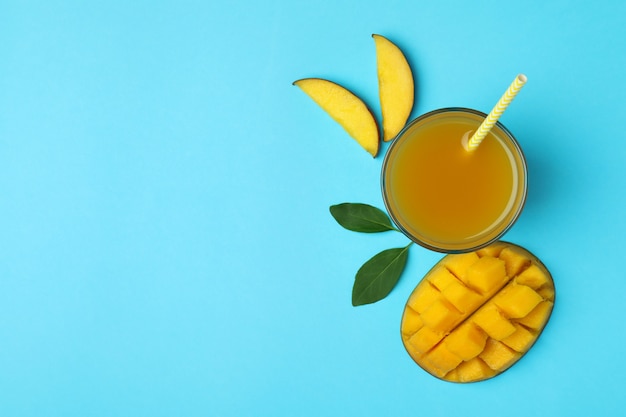 Ripe mango fruit and juice on blue surface