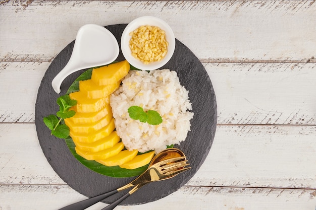 Mango maturo e riso appiccicoso con latte di cocco sulla superficie della pietra, dessert dolce tailandese nella stagione estiva.