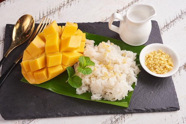 Ripe mango and sticky rice with coconut milk on stone surface, Thai sweet dessert on summer season.