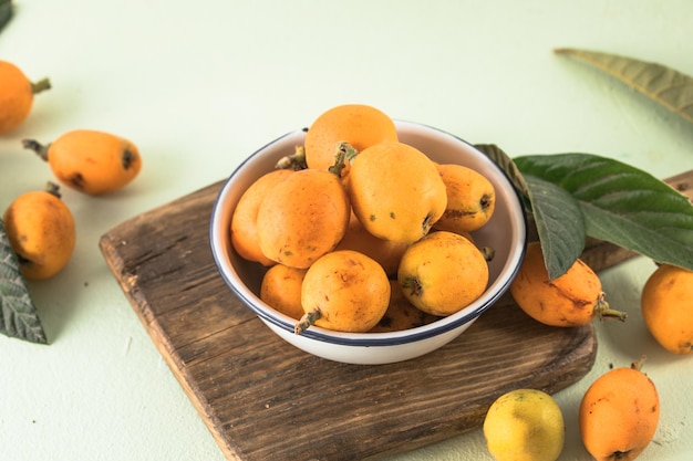 Ripe medlar fruit Eriobotrya japonica and green medlar leaves on wooden table Top view