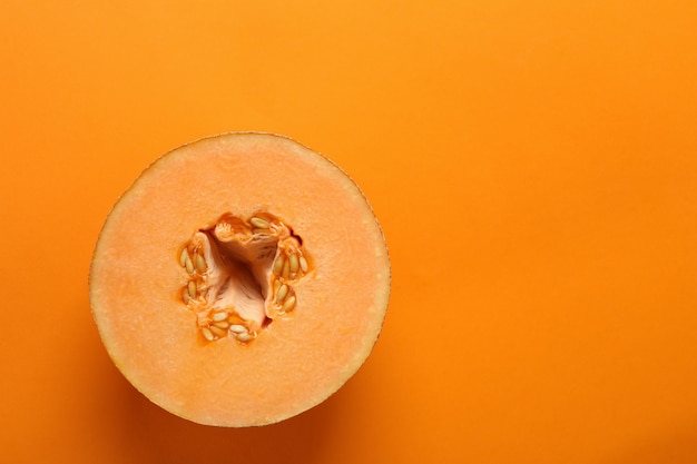 Ripe melon on orange background, space for text