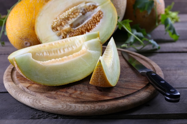 Ripe melons with green leaves on wooden table close up