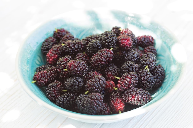 Ripe mulberry in bowl on a wooden table