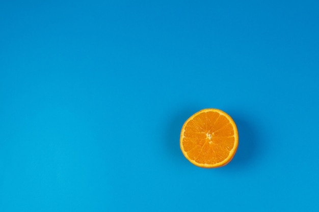 Arancio maturo tagliato a metà su sfondo blu vista dall'alto