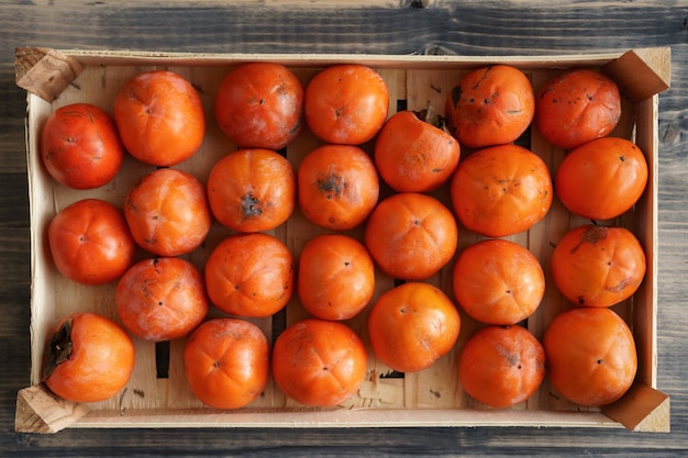 Ripe orange persimmons in a drawer the texture of the background is from persimmon fruit