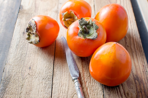 Ripe orange persimmons on an old wooden table