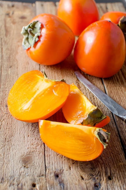 熟したオレンジ色の柿、古い木製のテーブル