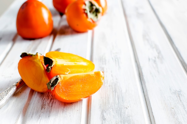 Ripe orange persimmons on an old wooden table