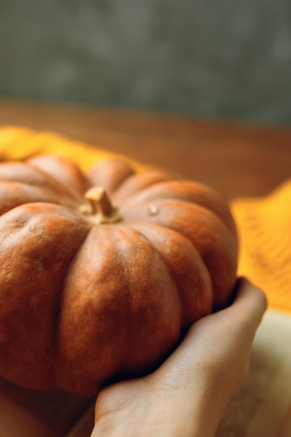 Zucca arancione matura in mani tavolo di legno e sfondo concretoil concetto di ringraziamento o sala...