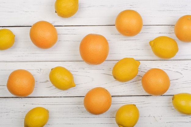 Arance e limoni maturi su tavole di legno bianche, vista dall'alto