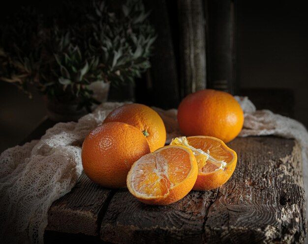 ripe oranges on a vintage dark wooden table with a napkin on a dark background