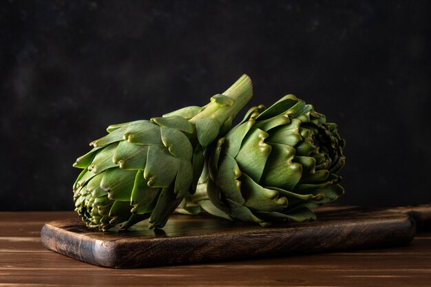 Carciofi organici maturi su una tavola di legno rustica.