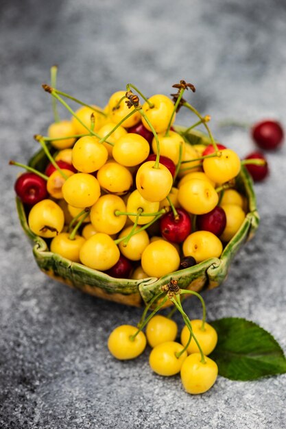 Ripe organic sweet cherries in a bowl on concrete background with copy space