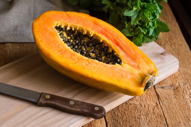 Ripe papaya cut in half on wood cutting board bunch of fresh mint