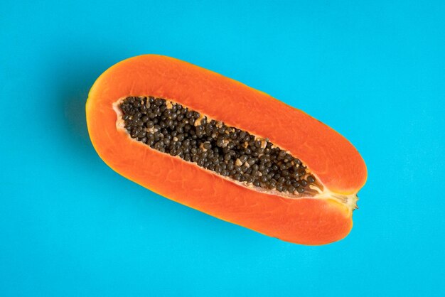 Ripe papaya fruit cut into half on blue background