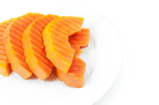 Ripe papaya fruit sliced on a white dish on white background