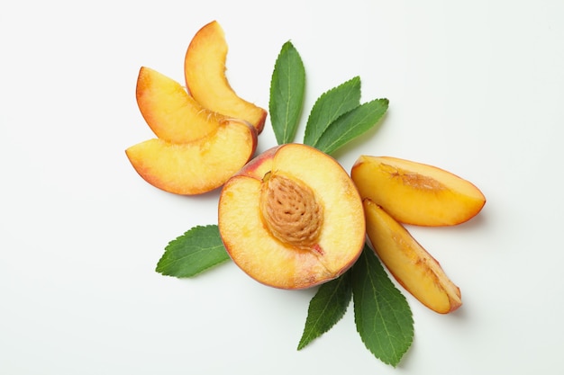 Ripe peach fruit with leaves on white background