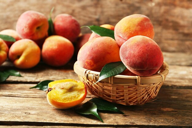 Ripe peaches in basket on wooden background