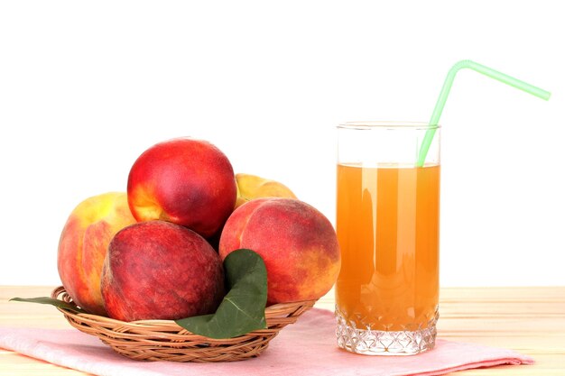 Ripe peaches and juice on wooden table on white background