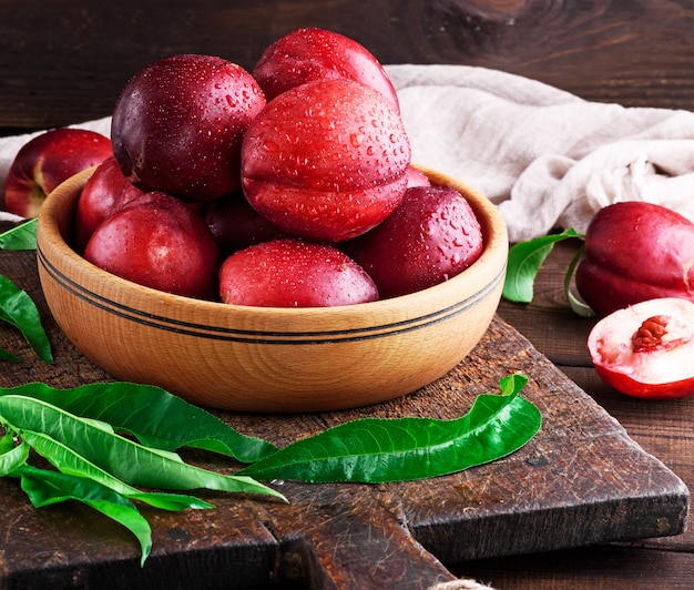 Ripe peaches nectarine in a brown wooden bowl