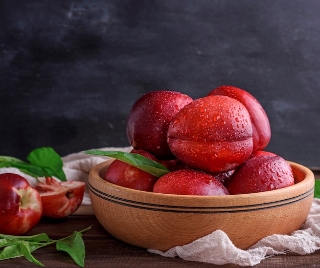 Ripe peaches nectarine in a brown wooden bowl