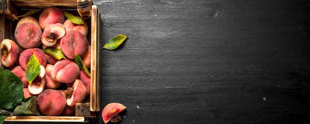 Ripe peaches in a wooden box. On the black chalkboard.