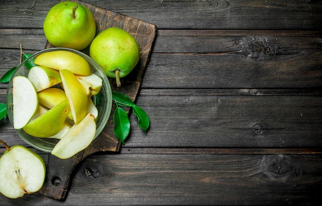 Photo ripe pear in a bowl on a cutting board with leaves