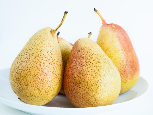 Ripe pear on white background. The cultivation of the pear in cool temperate climates extends to the remotest antiquity, and there is evidence of its use as a food since prehistoric times.