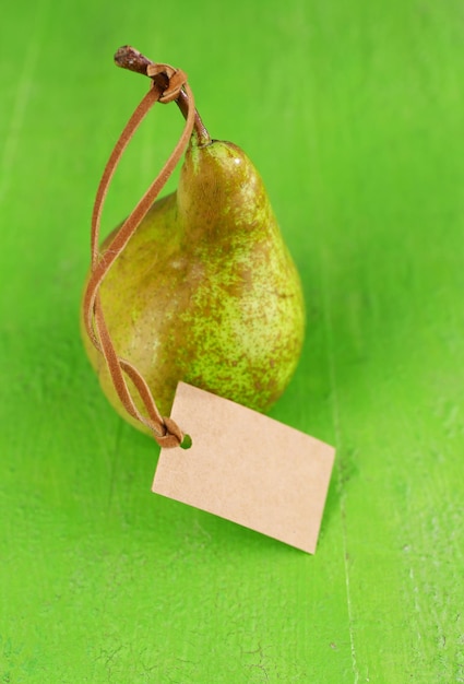 Photo ripe pear with paper tag on wooden background