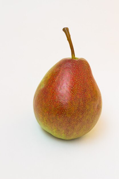 Ripe pear with sprig on a white table.