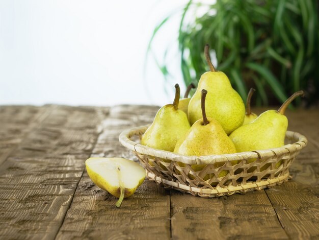 Ripe pears in a basket on a rustic wooden table.