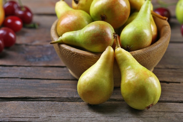 Photo ripe pears and cherries on wooden table close up