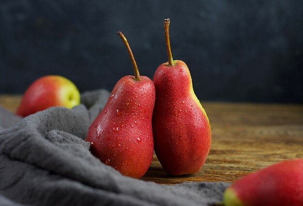 Ripe pears lie on a wooden table. There is a towel next to it