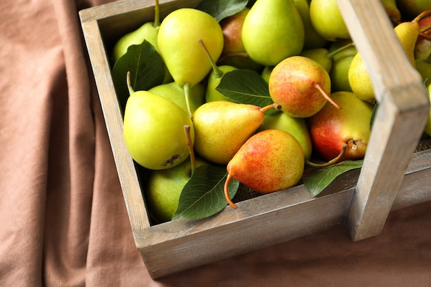 Ripe pears in wooden basket on fabric