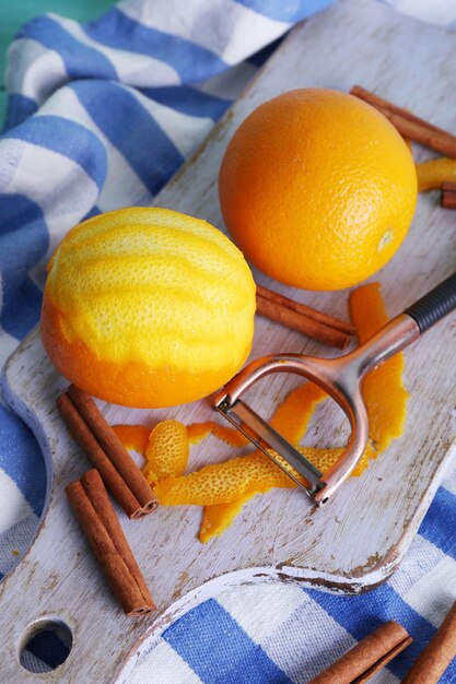 Foto arance mature e sbucciate e coltello per sbucciare sul tagliere su sfondo di tessuto