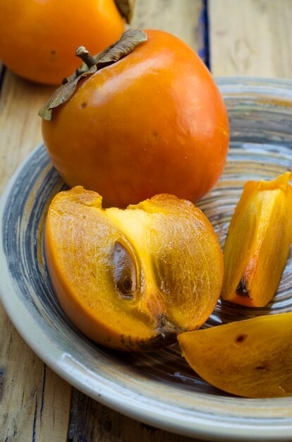 Ripe persimmon on a plate on a wooden table